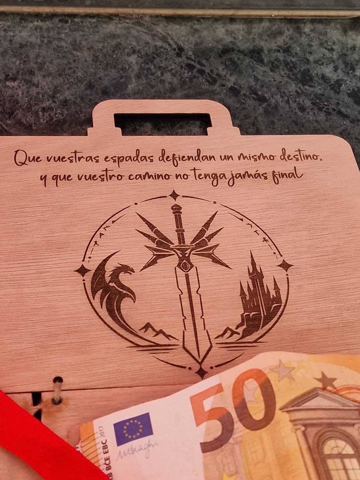 Detalle de la dedicatoria y el grabado interior de una espada, un dragón y un castillo sobre la madera